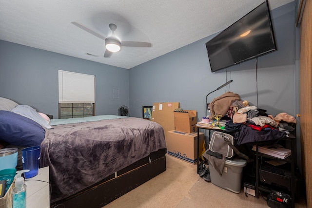 bedroom with ceiling fan, light colored carpet, and a textured ceiling