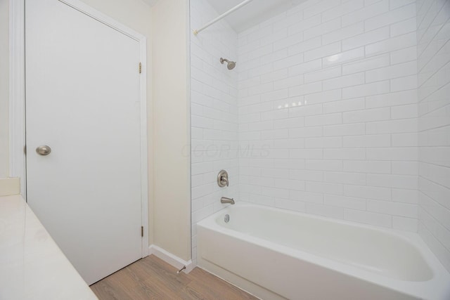 bathroom with hardwood / wood-style flooring and tiled shower / bath