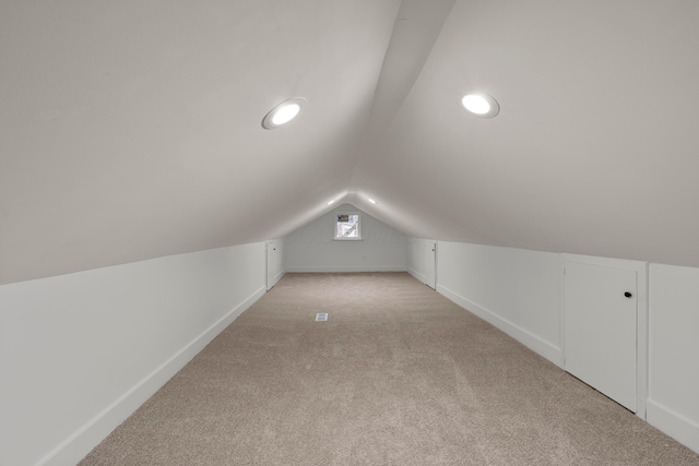 additional living space featuring lofted ceiling and light carpet