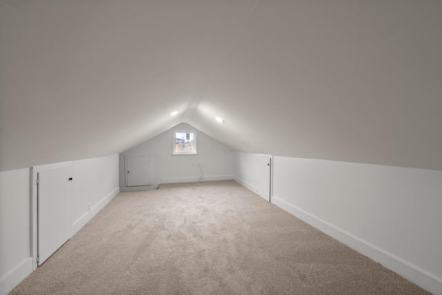 additional living space featuring vaulted ceiling and light colored carpet