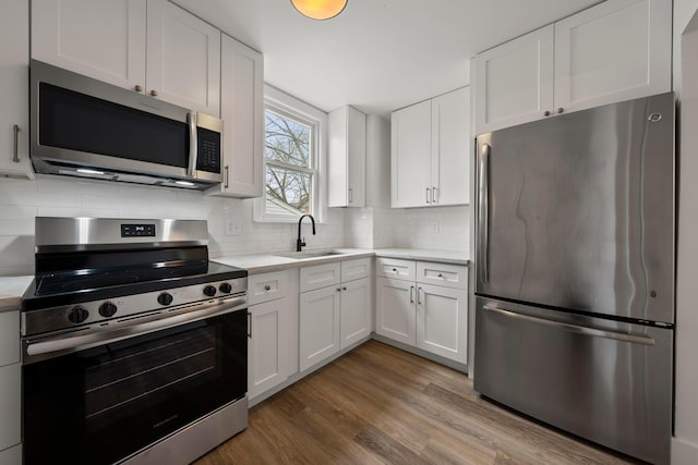 kitchen with stainless steel appliances, sink, decorative backsplash, and white cabinets