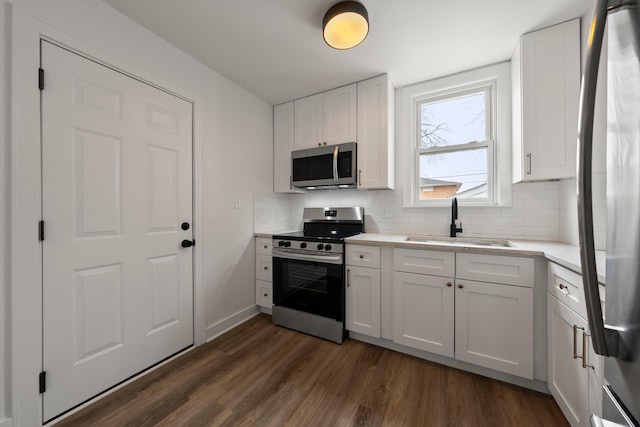 kitchen with appliances with stainless steel finishes, tasteful backsplash, sink, white cabinets, and dark hardwood / wood-style flooring