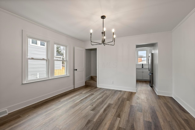 unfurnished dining area featuring an inviting chandelier, ornamental molding, and dark hardwood / wood-style floors