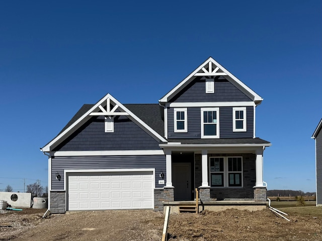 craftsman house with stone siding, a porch, driveway, and a garage