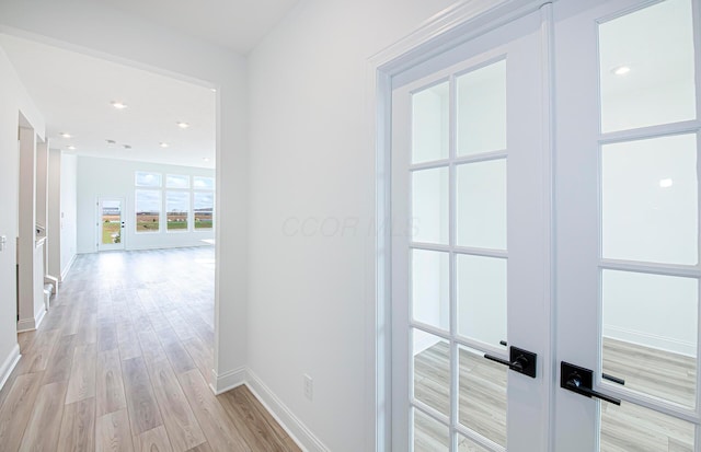 corridor with light wood-type flooring, french doors, and baseboards
