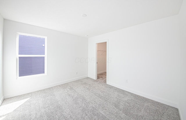 spare room featuring baseboards and light carpet