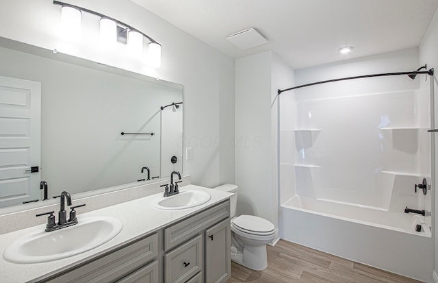 bathroom with a sink, bathtub / shower combination, wood finished floors, and toilet