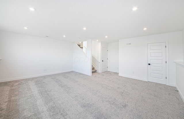 empty room with baseboards, recessed lighting, light carpet, and stairs