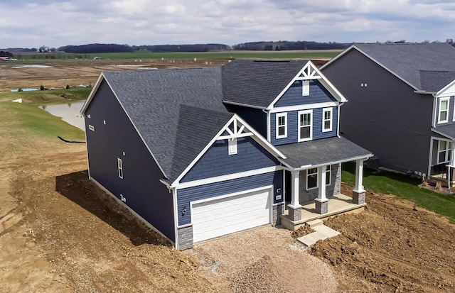 craftsman house featuring a shingled roof, covered porch, a garage, and driveway