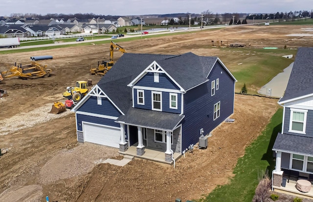 view of front of house with a porch, driveway, a garage, and a residential view