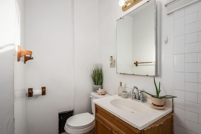 bathroom featuring vanity, toilet, and tile walls