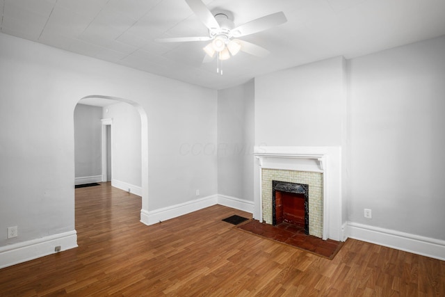 unfurnished living room with ceiling fan, wood-type flooring, and a tile fireplace