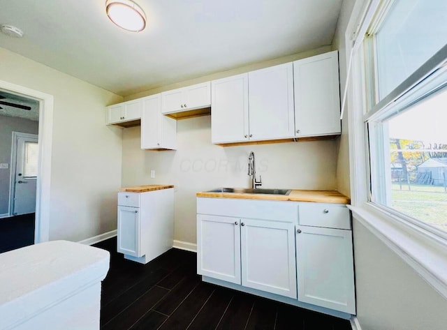 kitchen with butcher block counters, sink, white cabinets, and dark hardwood / wood-style flooring