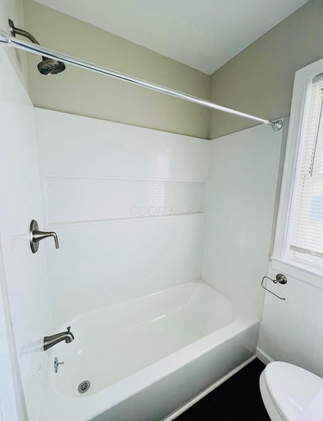 bathroom featuring tile patterned floors, toilet, and bathing tub / shower combination