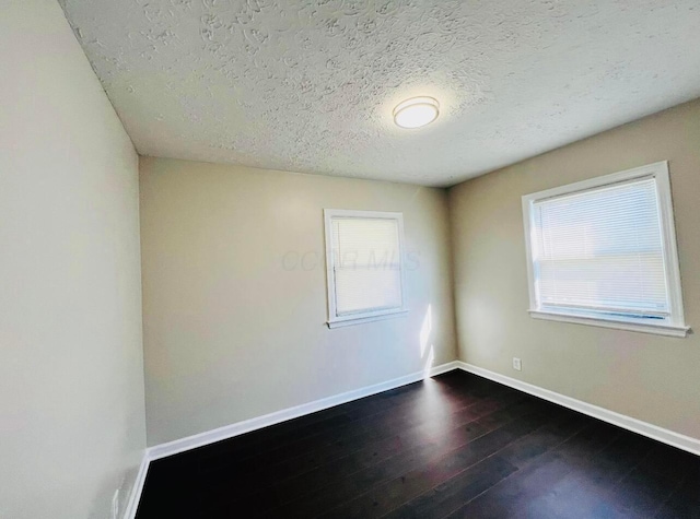 empty room with hardwood / wood-style flooring and a textured ceiling