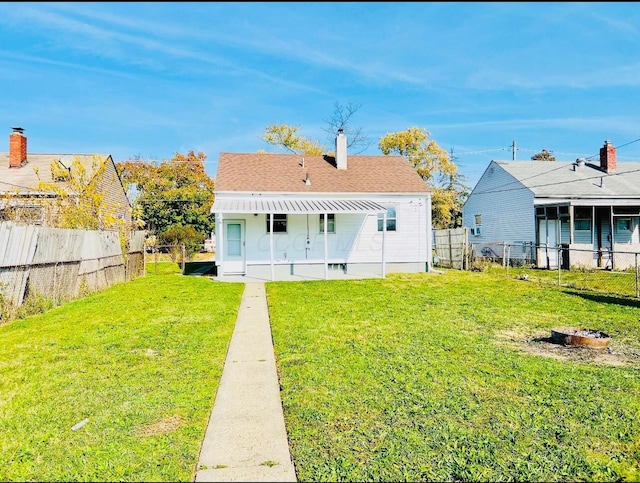 back of property featuring a fire pit and a lawn