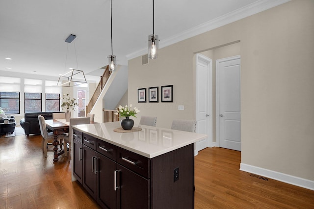 kitchen featuring pendant lighting, dark hardwood / wood-style floors, crown molding, and a center island