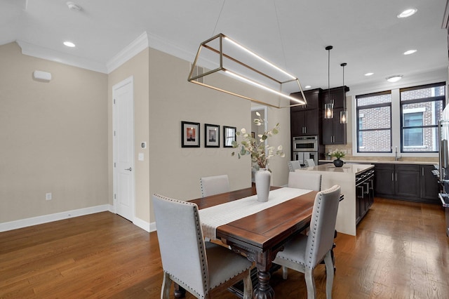 dining area featuring dark wood-type flooring, crown molding, and sink