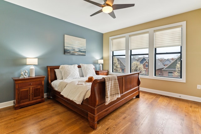 bedroom featuring visible vents, baseboards, ceiling fan, and wood finished floors
