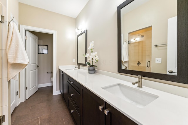 full bathroom featuring toilet, double vanity, a sink, and a shower stall