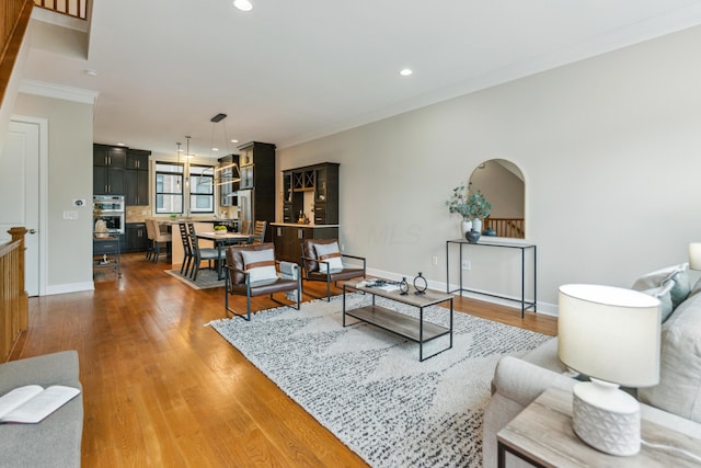 living room with recessed lighting, baseboards, crown molding, and wood finished floors