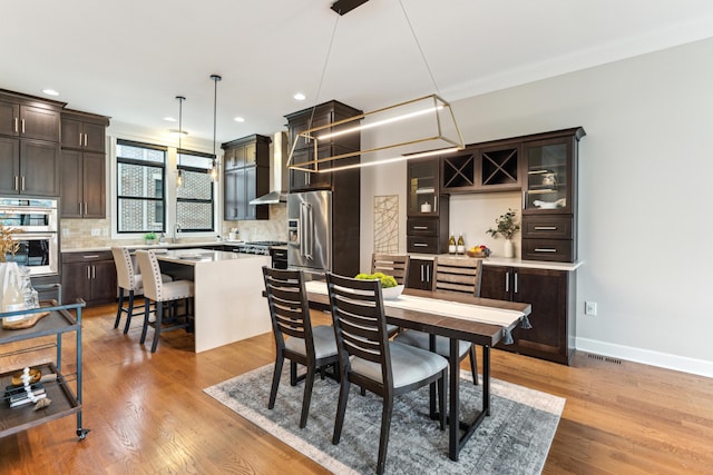 dining room featuring ornamental molding, baseboards, recessed lighting, and light wood-style floors