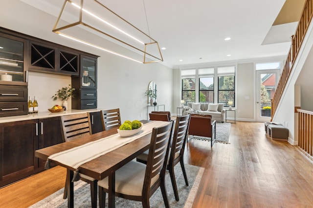 dining room with baseboards, ornamental molding, recessed lighting, stairway, and light wood-style floors