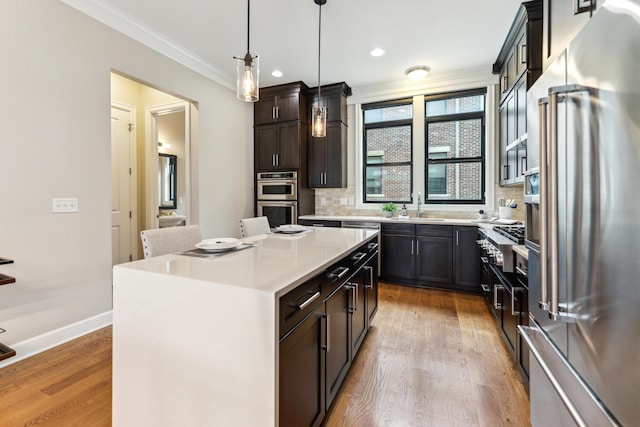 kitchen with crown molding, tasteful backsplash, light countertops, stainless steel appliances, and light wood finished floors