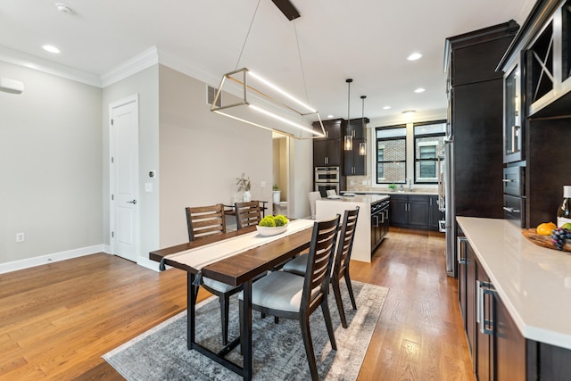 dining area featuring ornamental molding, baseboards, light wood finished floors, and recessed lighting