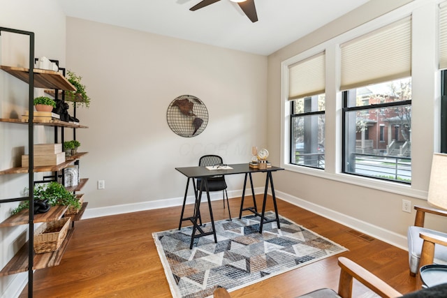 home office with wood finished floors, ceiling fan, baseboards, and visible vents
