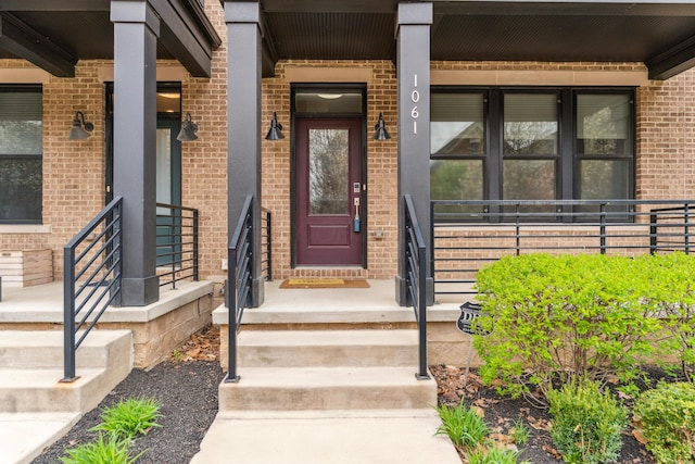 entrance to property featuring brick siding and covered porch