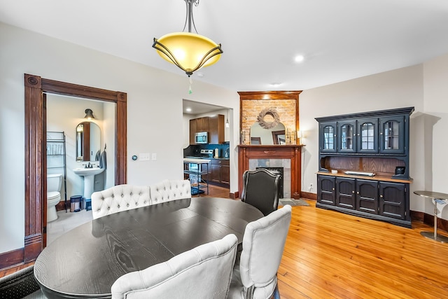 dining space with a tiled fireplace, sink, and light hardwood / wood-style flooring