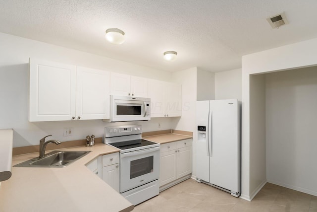 kitchen with white appliances, sink, a textured ceiling, and white cabinets