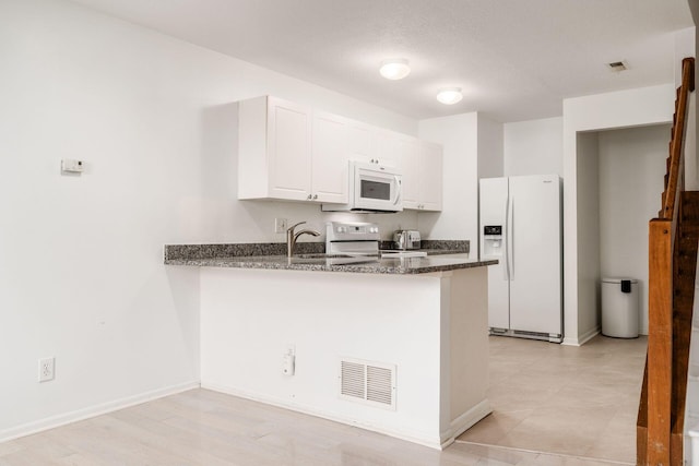 7083 Gallant Fox Dr Unit 4, New Albany, OH 43054 - kitchen with white appliances, a peninsula, white cabinetry, dark stone counters, and a sink