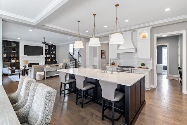 kitchen featuring decorative light fixtures, a large island, custom range hood, open floor plan, and white cabinetry