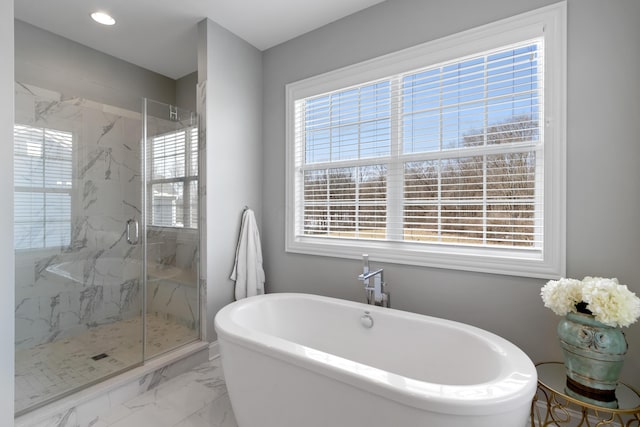 bathroom with marble finish floor, plenty of natural light, a marble finish shower, and a freestanding bath