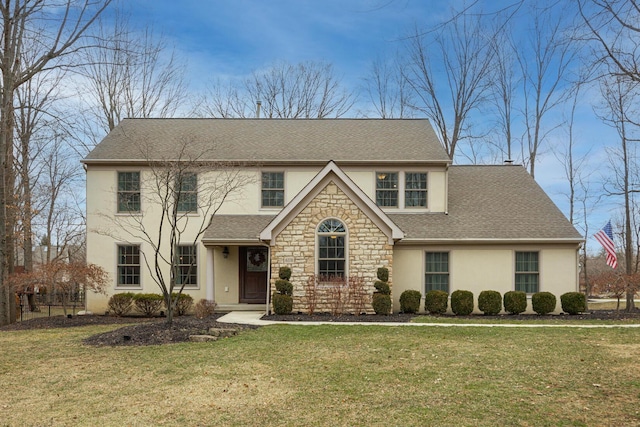 view of front facade featuring a front yard, stone siding, and stucco siding