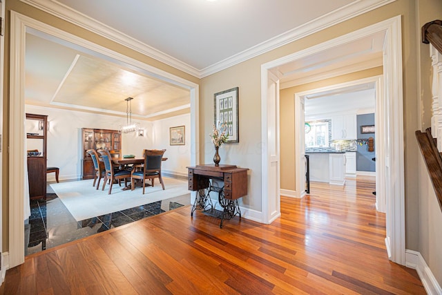 dining room with a chandelier, crown molding, baseboards, and hardwood / wood-style floors