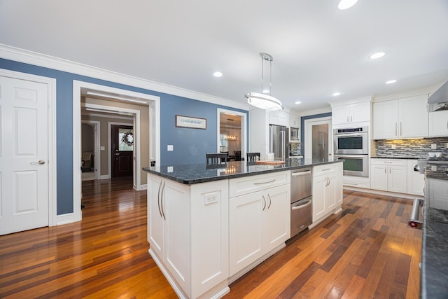 kitchen with a warming drawer, ornamental molding, a kitchen island, appliances with stainless steel finishes, and white cabinets