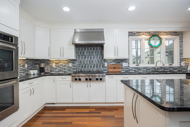 kitchen with backsplash, stainless steel appliances, dark wood-type flooring, and wall chimney exhaust hood