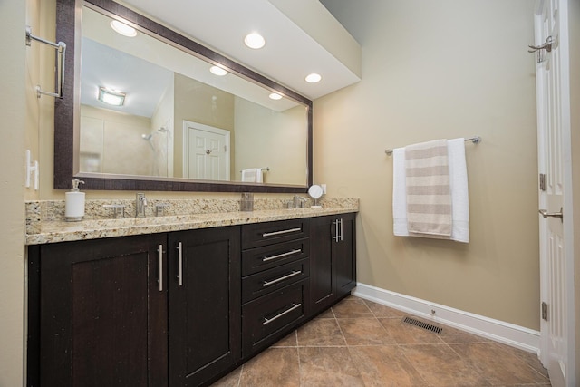 full bathroom featuring visible vents, a sink, double vanity, baseboards, and walk in shower