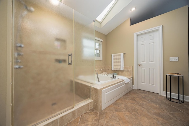 bathroom featuring lofted ceiling with skylight, a shower stall, baseboards, and a garden tub