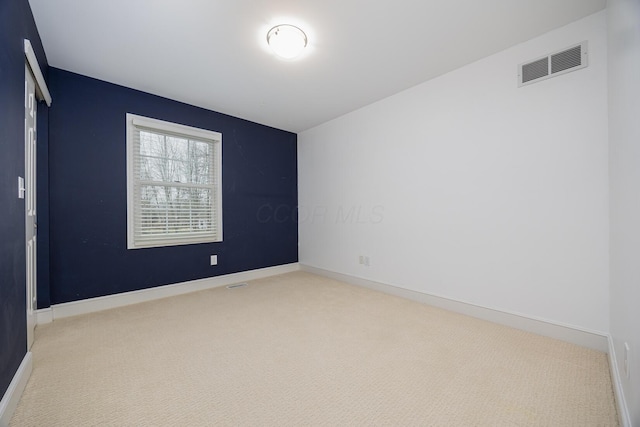 carpeted spare room featuring visible vents and baseboards