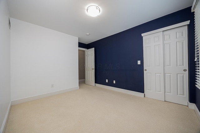 unfurnished bedroom featuring a closet, carpet floors, and baseboards