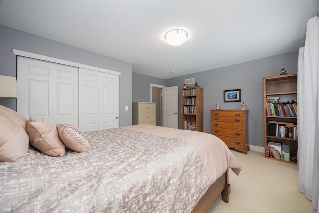 bedroom with a closet, baseboards, light colored carpet, and visible vents