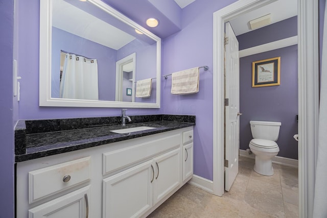 full bath featuring toilet, vanity, and baseboards