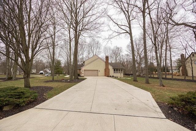 view of side of property with an attached garage, a lawn, a chimney, and stucco siding