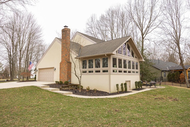 view of side of property with concrete driveway, stucco siding, a chimney, a yard, and an attached garage