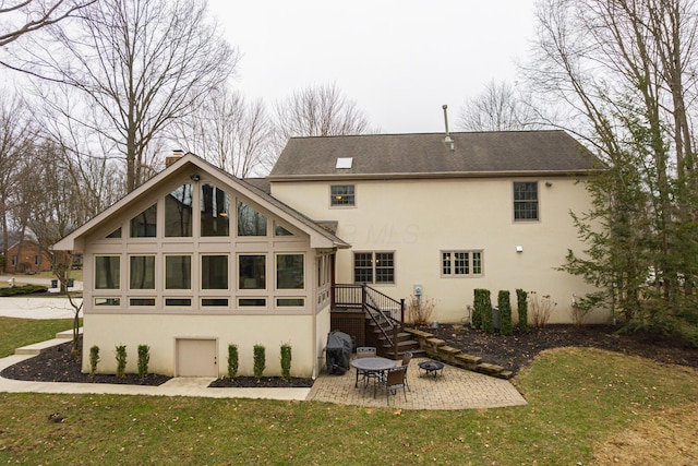 back of property featuring stucco siding, a patio, a yard, and a chimney