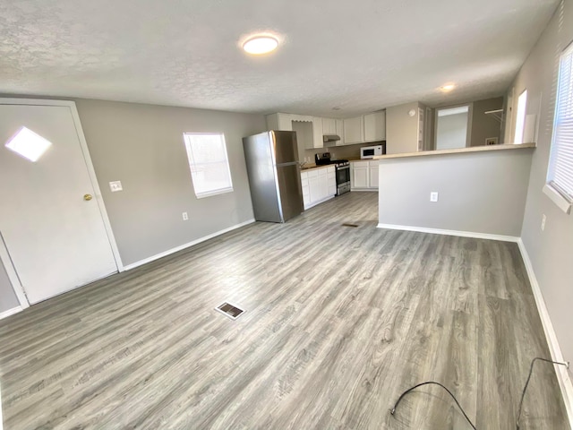 unfurnished living room featuring light hardwood / wood-style floors and a textured ceiling